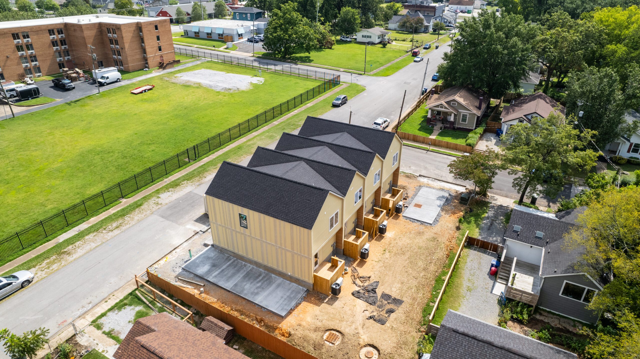 Aerial view of the rear of the four homes under construction, with concrete pads, condensers and screened enclosures along the back