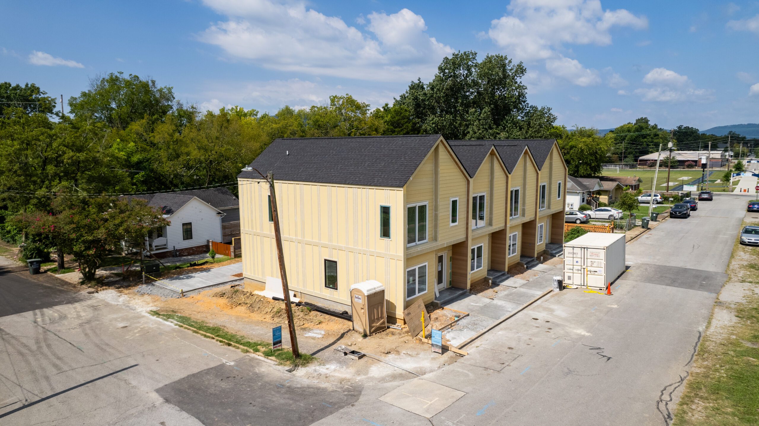 The Beech Street homes under construction seen from the corner, with the sidewalk, curb and neighboring houses of Highland Park around them