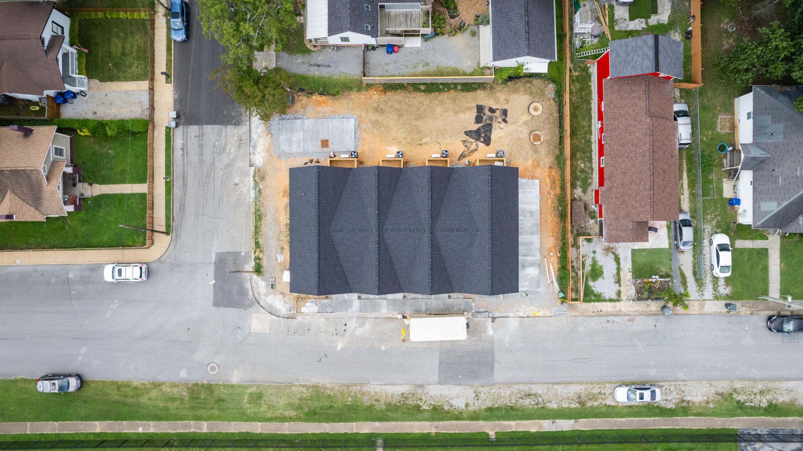 Overhead photo of the same lot with four attached homes built, showing the shared roof line, rear patios, driveway and new sidewalk