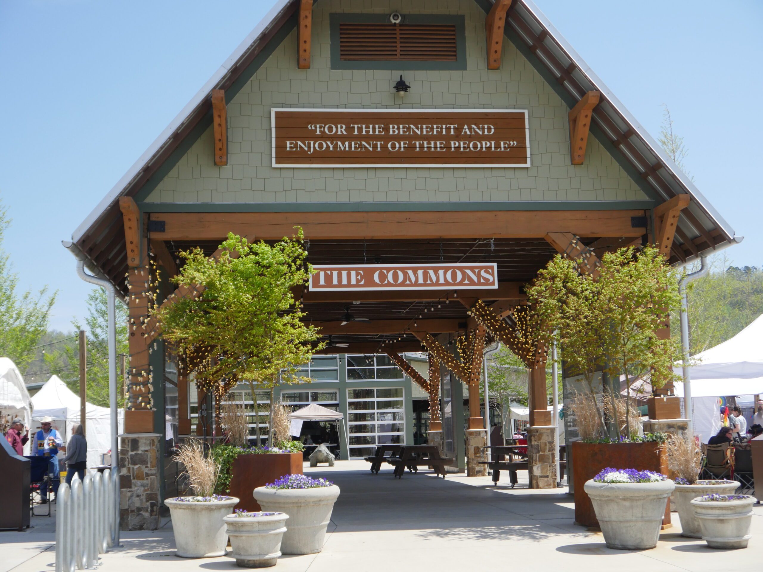 The open timber pavilion at the Commons with planters and market tents on either side