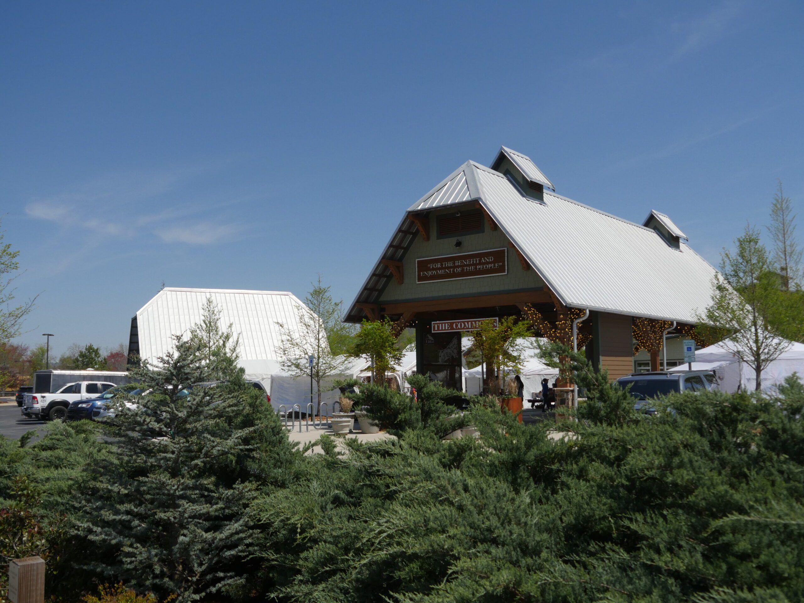 The Commons pavilion and Founders Hall seen over evergreen planting from the parking area