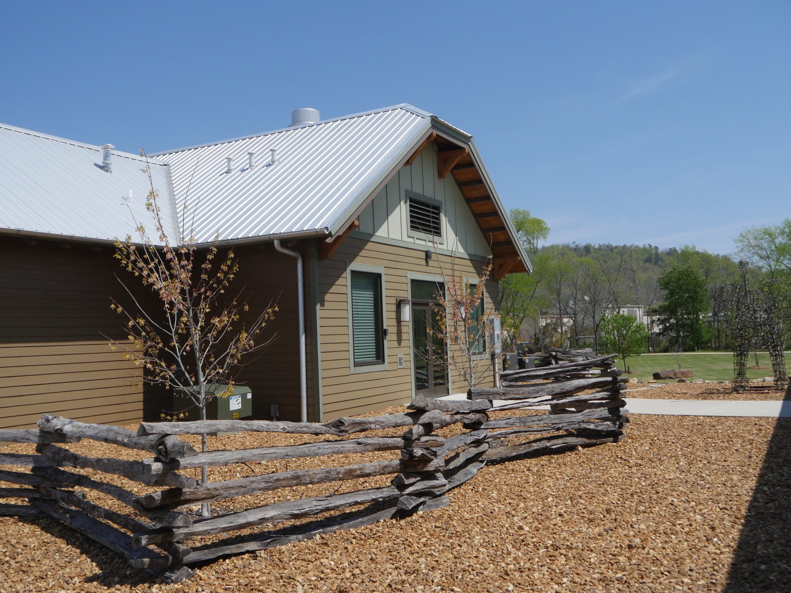 A split-rail fence and a bed of fine gravel alongside one of the park buildings