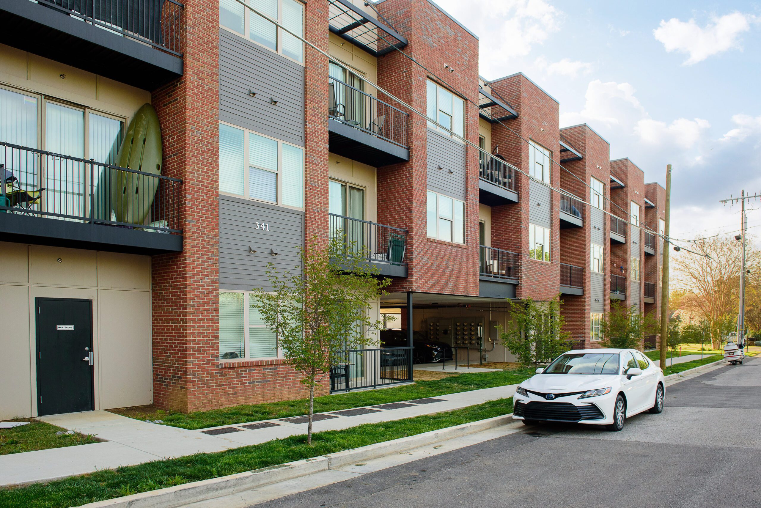 The brick and panel facade at 548 Cherokee Boulevard from the side street, with stepped bays, balconies, a lawn strip and the covered parking level below