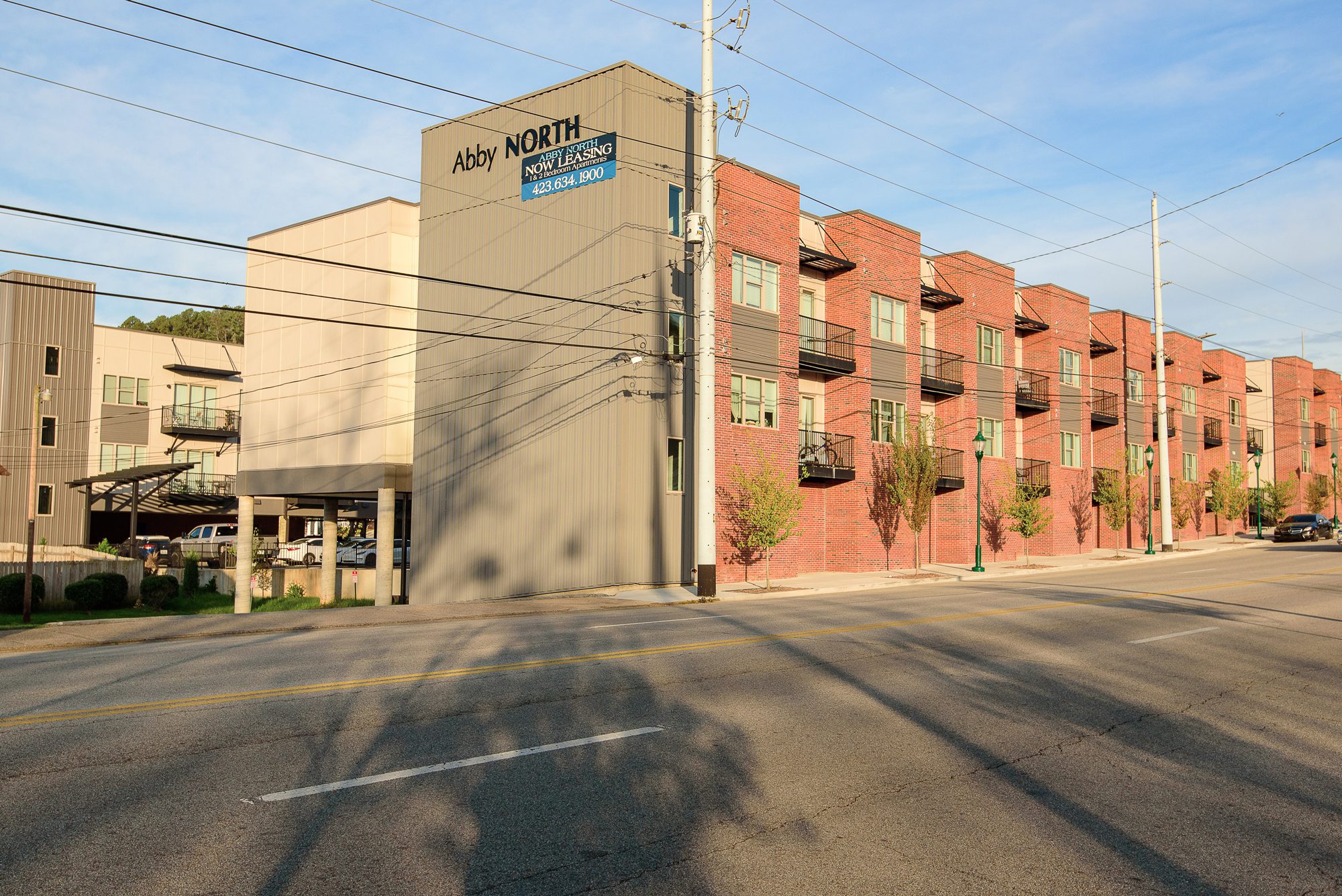 Close view along the facade at 548 Cherokee Boulevard, showing balconies, the maintenance entry, the sidewalk and the planted verge at the curb