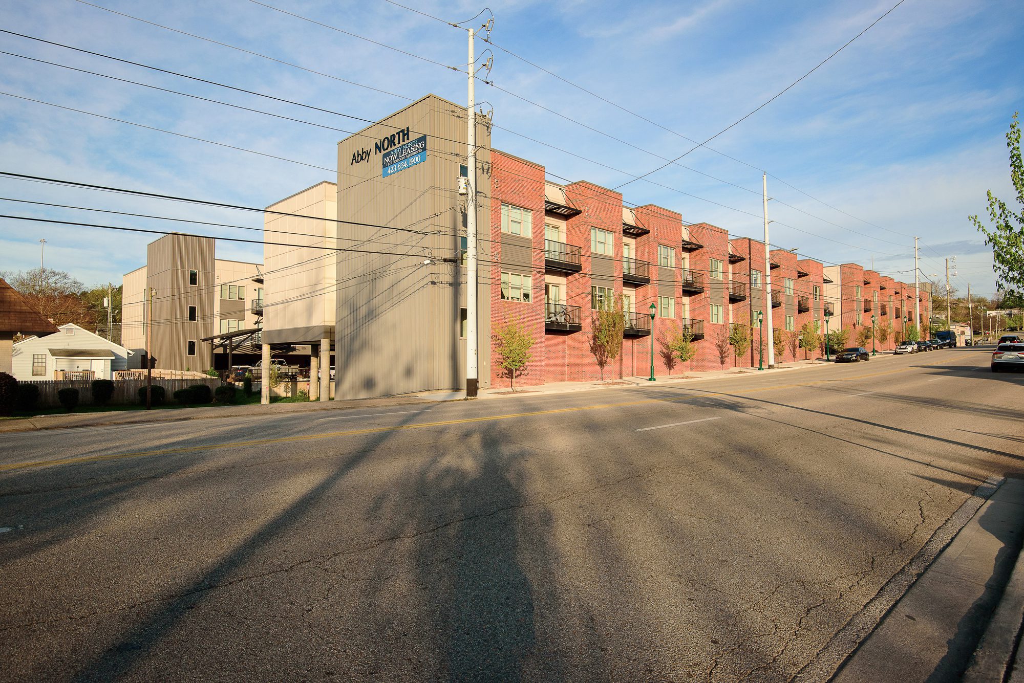 The Abby North apartment building at 548 Cherokee Boulevard seen along the street, three floors of brick and panel facade with balconies above ground-level parking