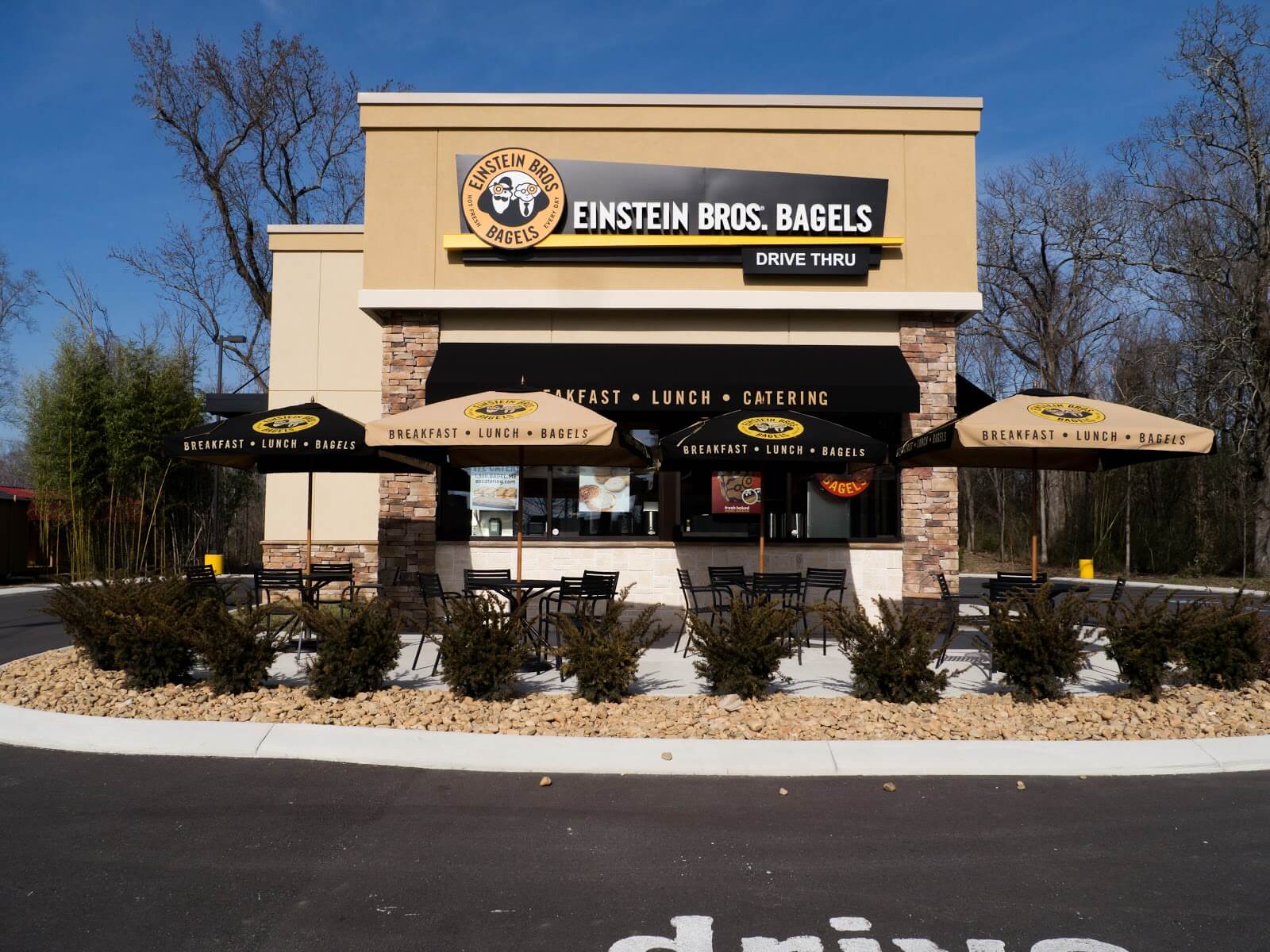 Einstein Bros. Bagels storefront with patio seating and drive-thru signage