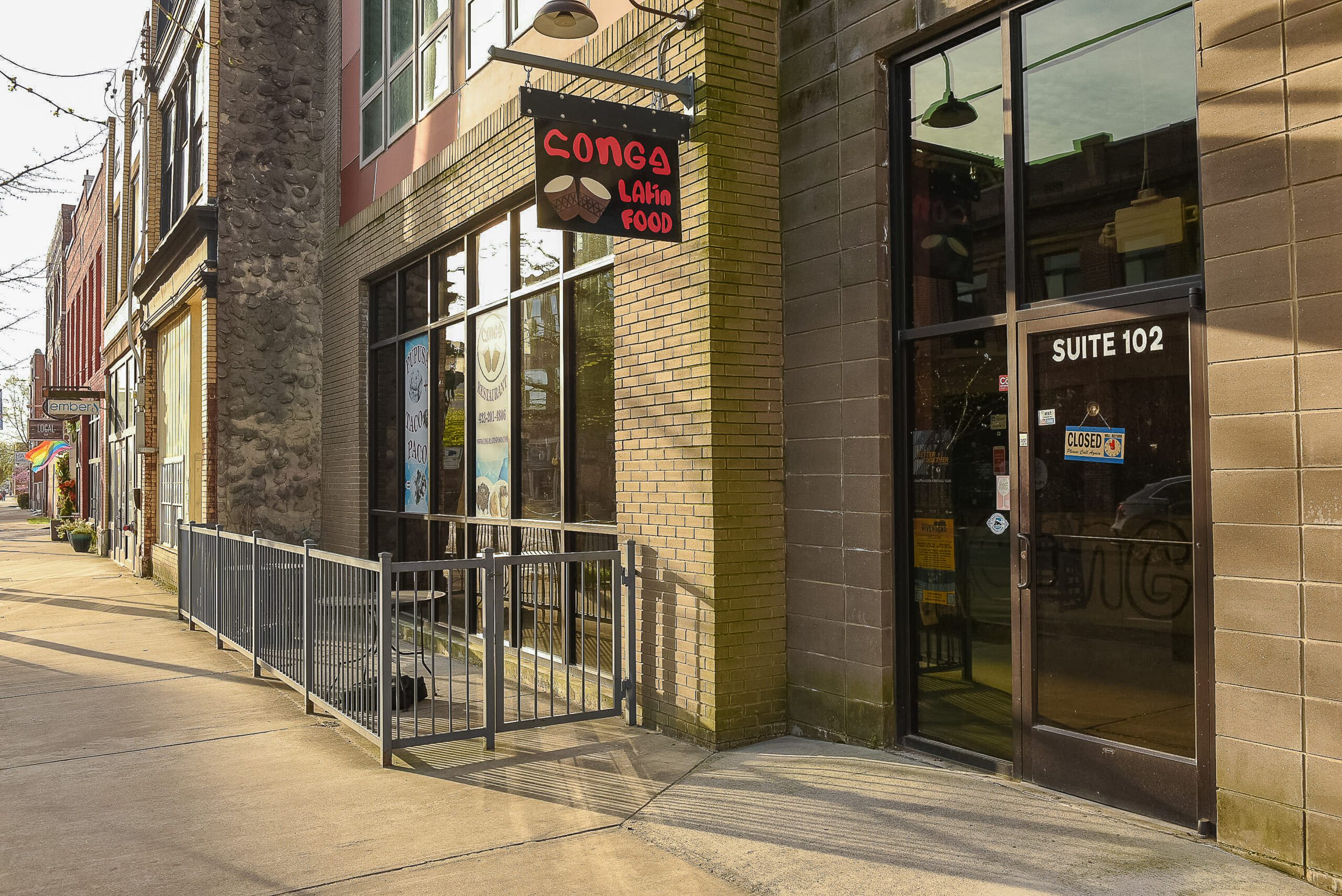 The corner entrance at street level, with a restaurant storefront, railed patio and suite door