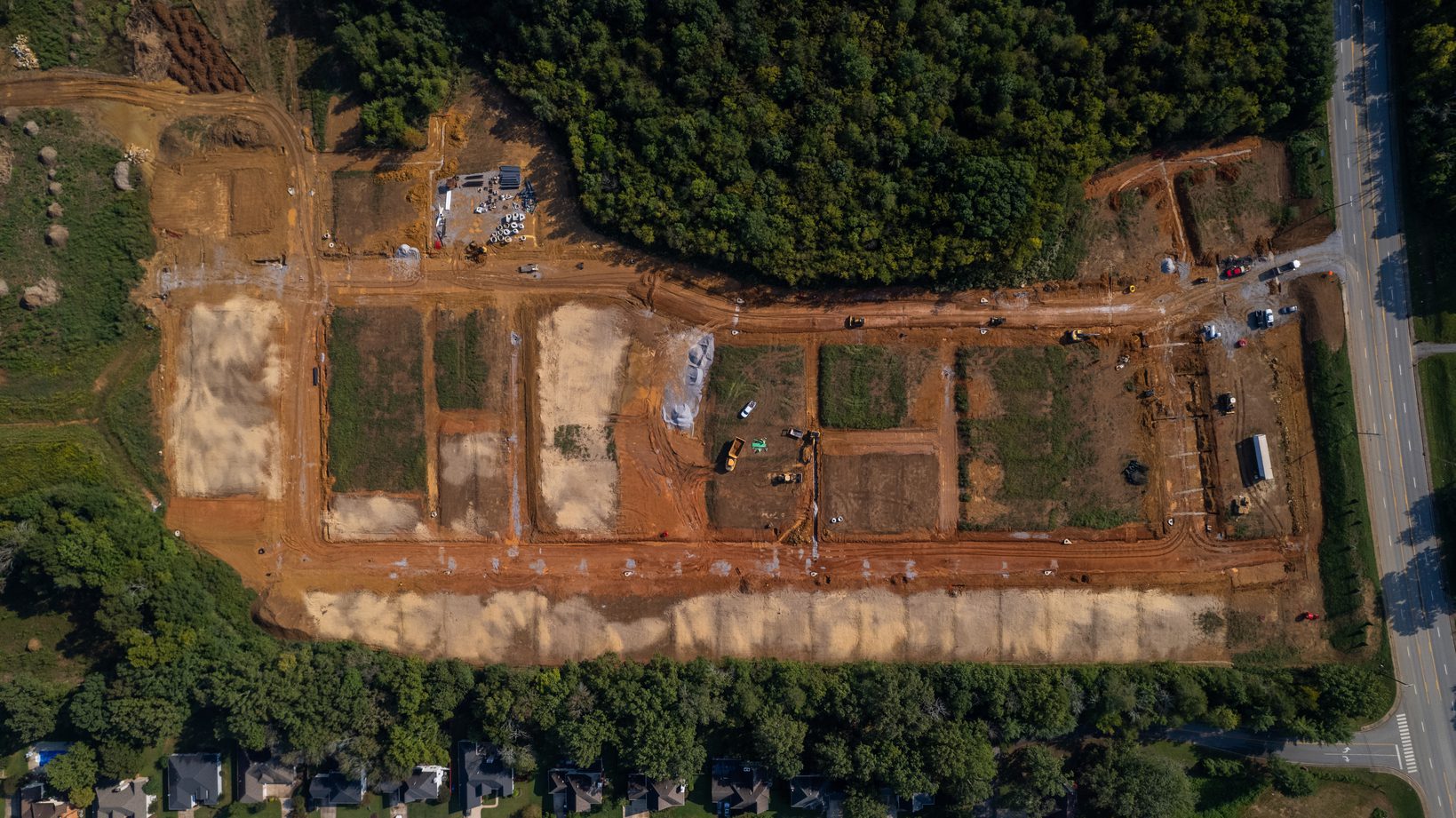 Overhead aerial of The Farmstead site, graded lots and streets set between woodland and Hixson Pike