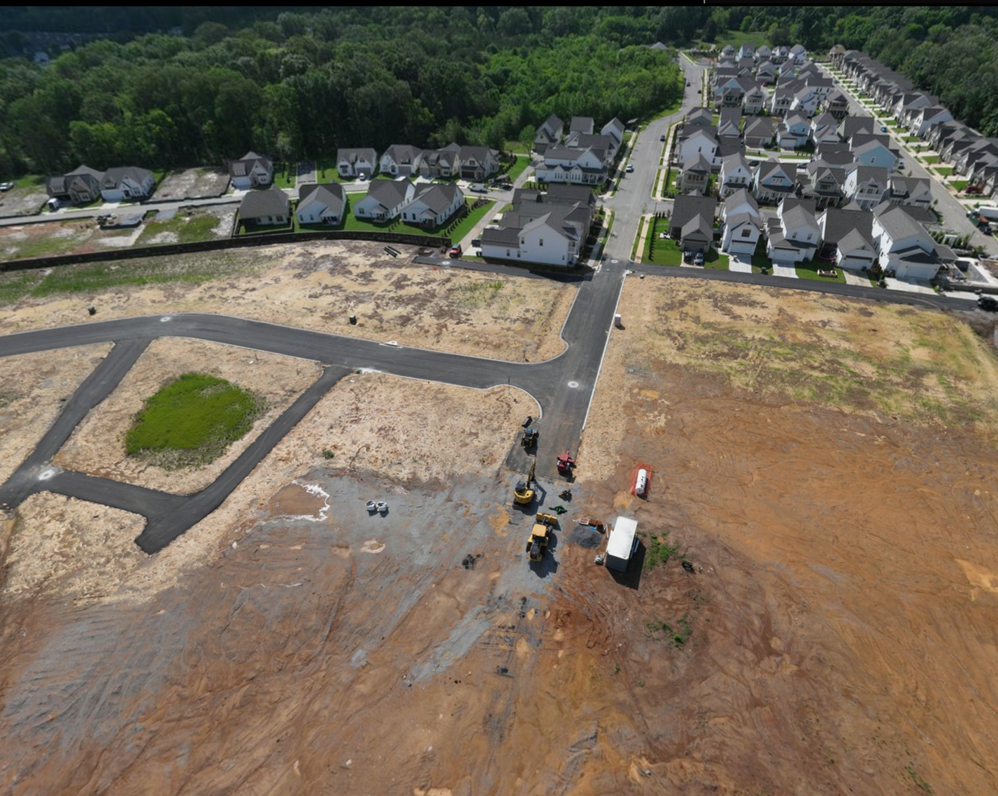 Aerial view of new streets and graded lots at The Farmstead Phase 2 meeting the finished homes of Phase 1