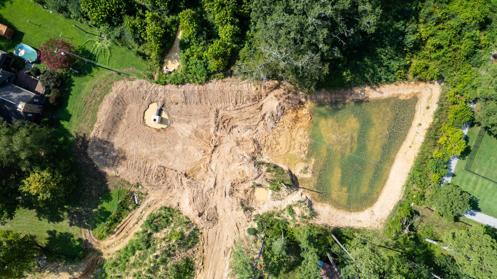 Overhead view of a detention pond under construction beside the woodland