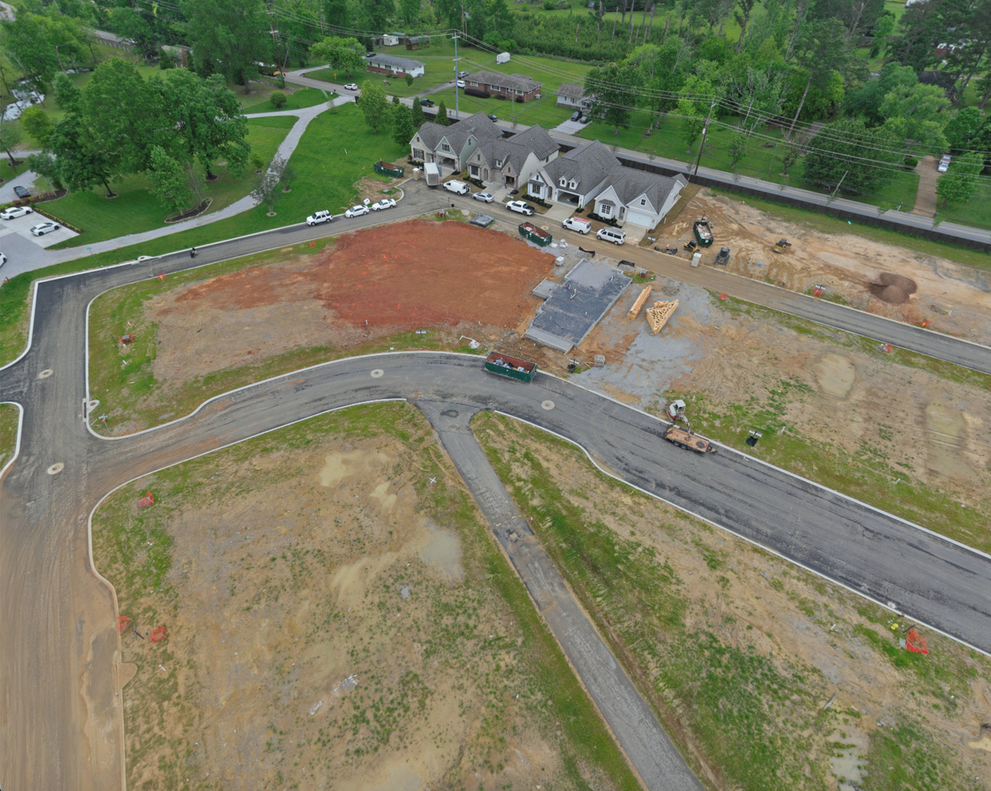 Aerial view of new curb and asphalt streets with graded lots