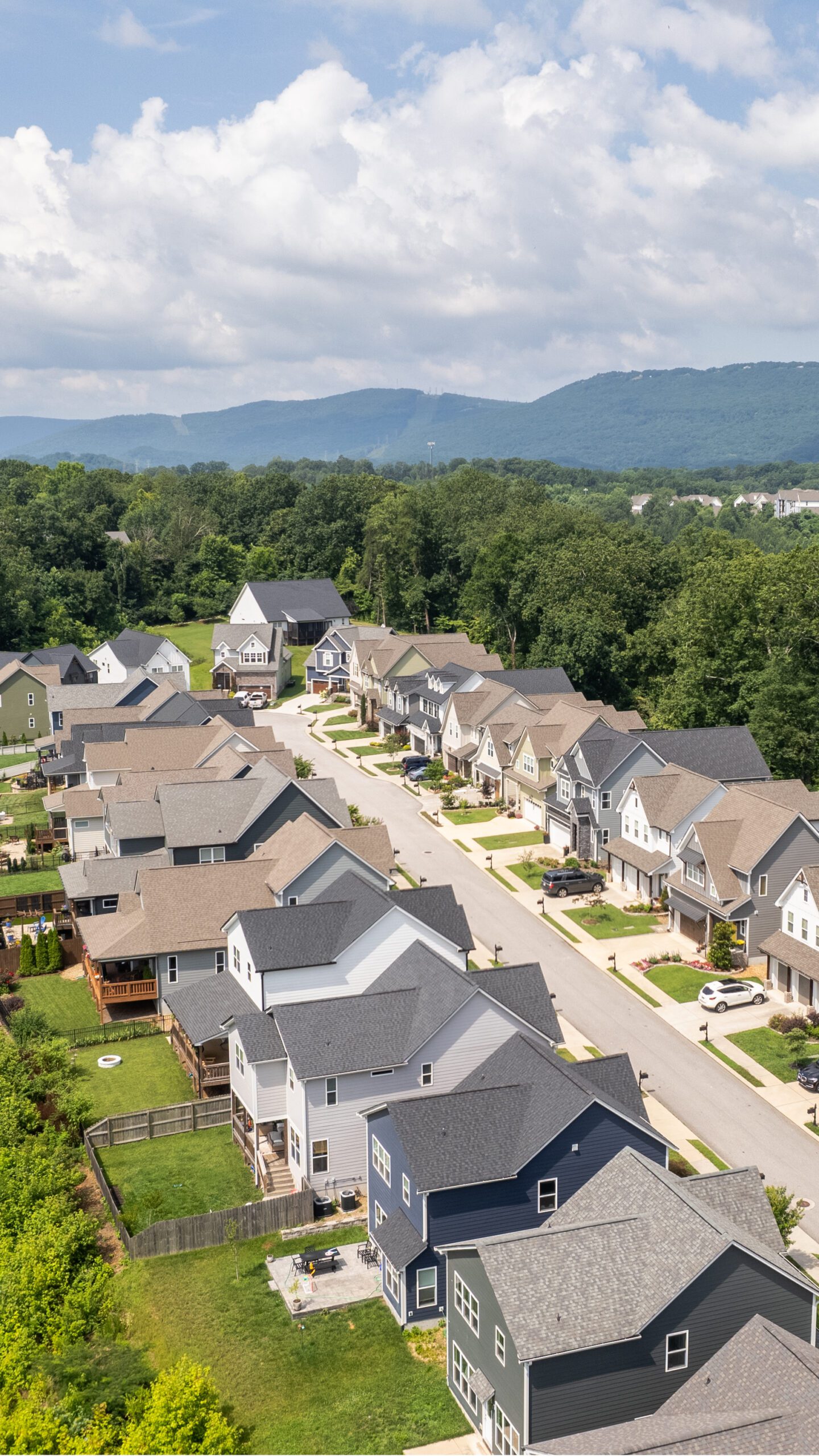 Aerial view along the street at Northpoint Ridge showing finished homes, driveways and rear yards on the ridgetop with mountains in the distance
