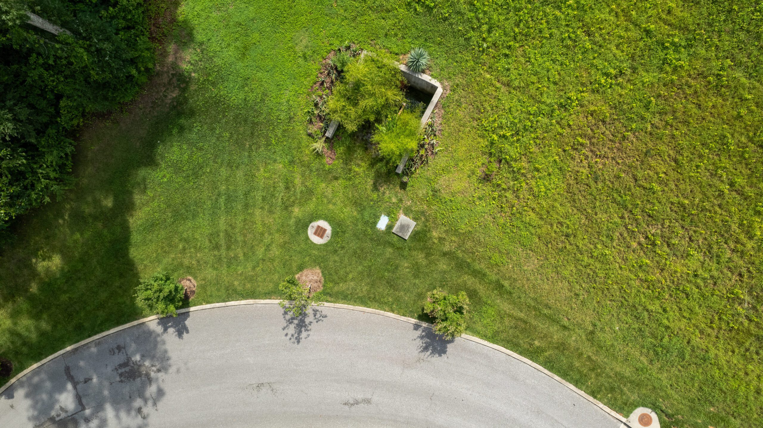 Overhead view of a stormwater outlet structure and planted basin in the grass beside a cul-de-sac at Northpoint Ridge, with a curb inlet nearby