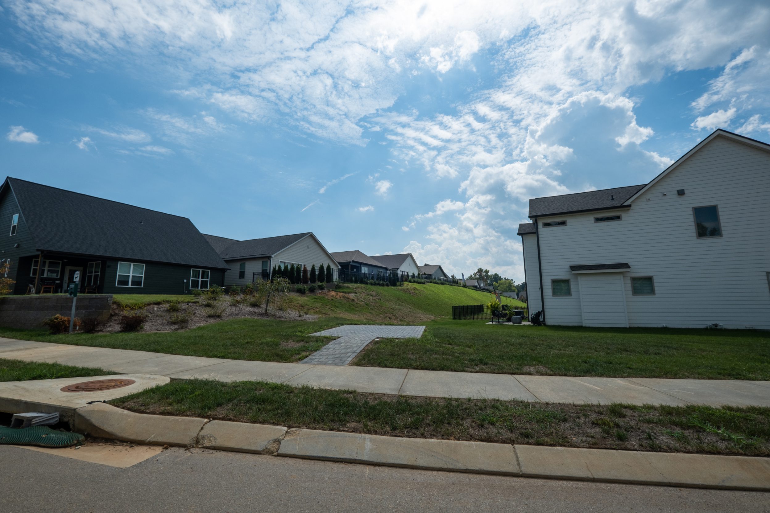Street-level view at Painted Ridge of a graded, planted greenway between homes with a paver path and sidewalk