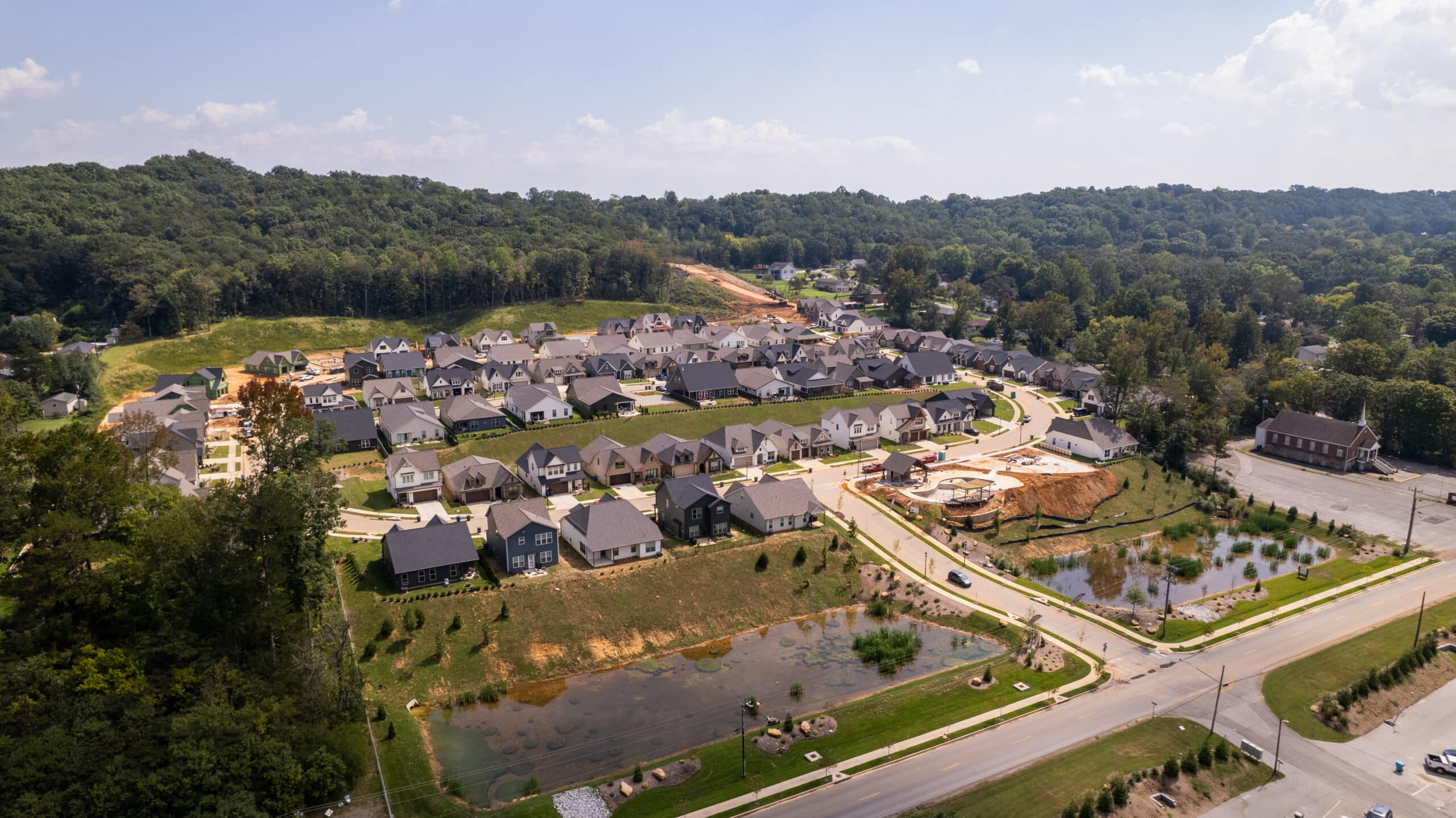 Aerial view of the Painted Ridge community, finished homes, streets and detention ponds set against wooded ridges
