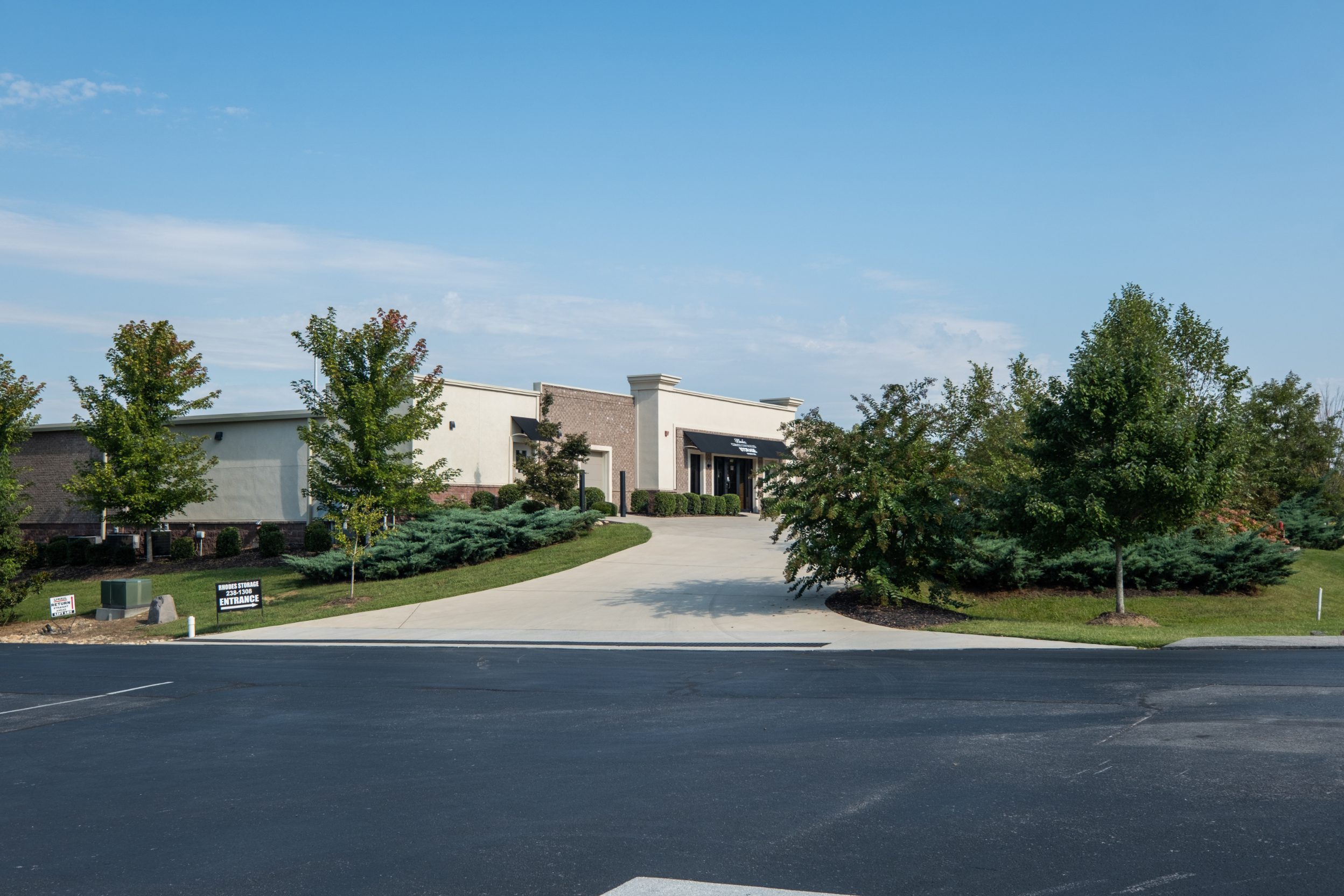 Concrete entrance drive to Rhodes Storage between planted beds