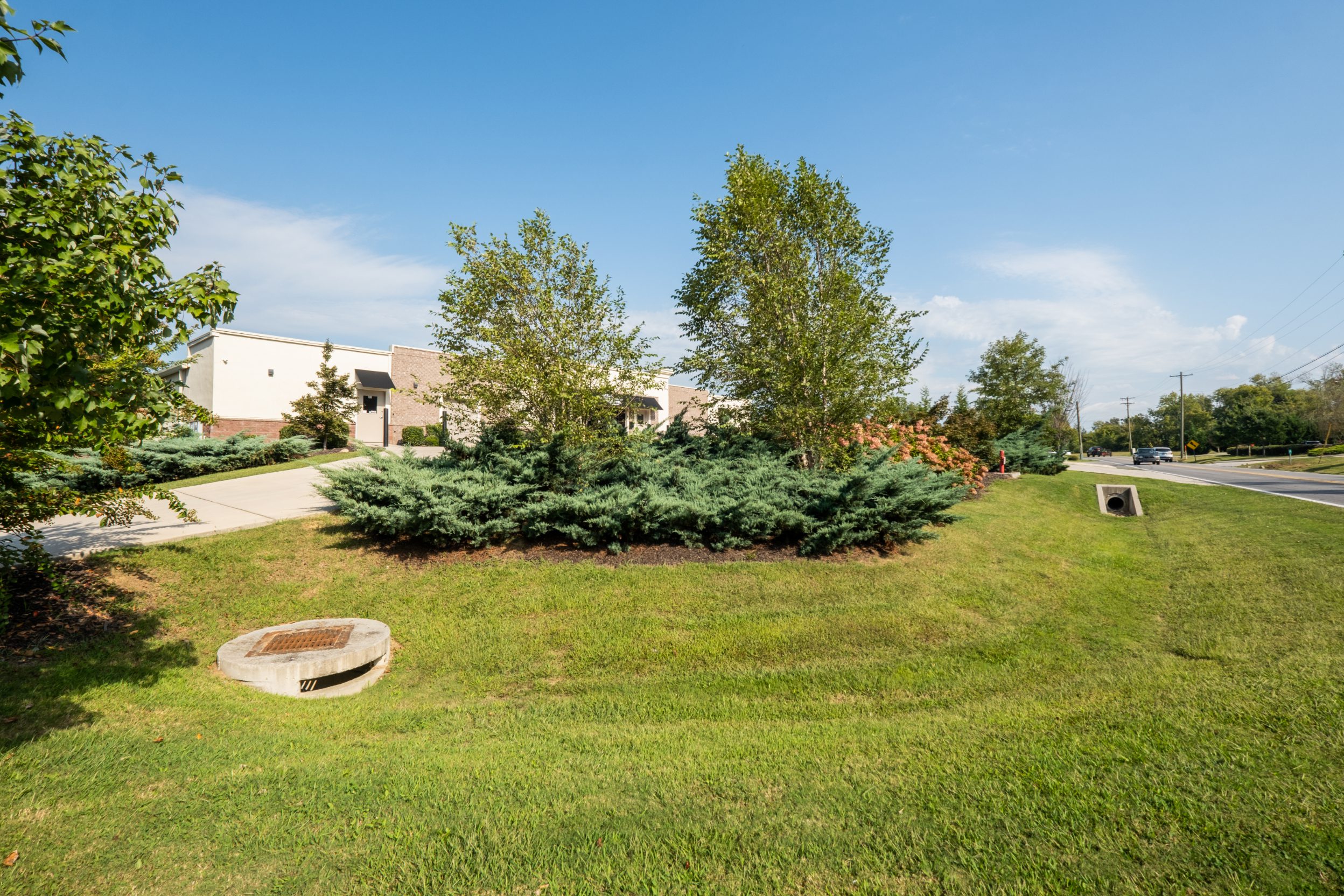 Planted beds and a drainage structure set into the lawn beside the building